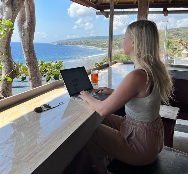 Andrae working on her laptop with an ocean view
